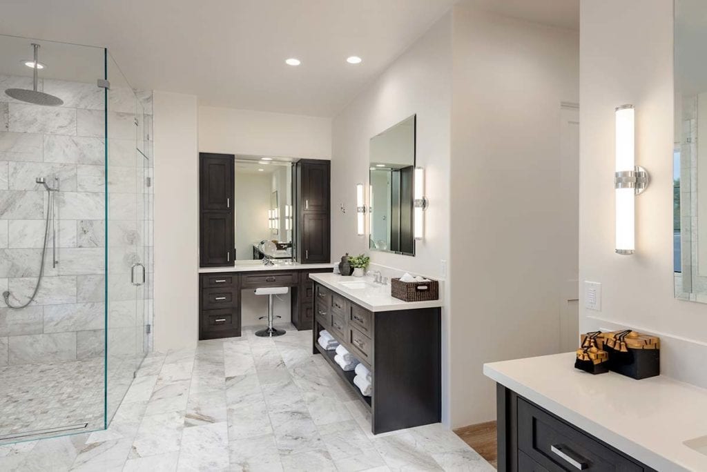 Luxury bathroom designed with glass shower, vanity, tile floors, two sinks, and accent lighting.